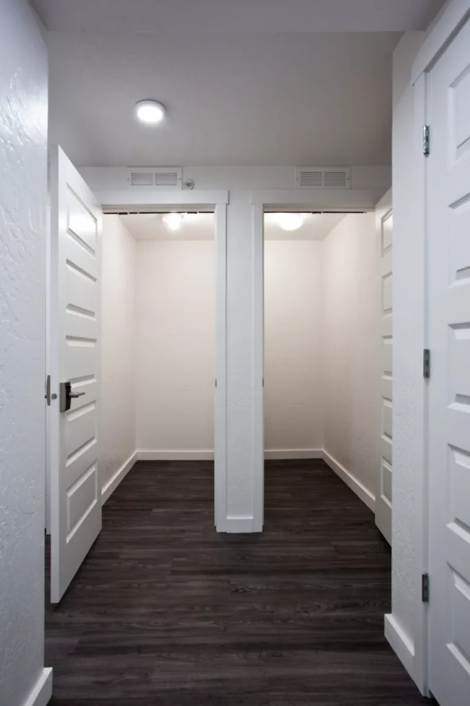 Hallway leading to two walk-in closets side by side. White doors and stainless steel hardware.