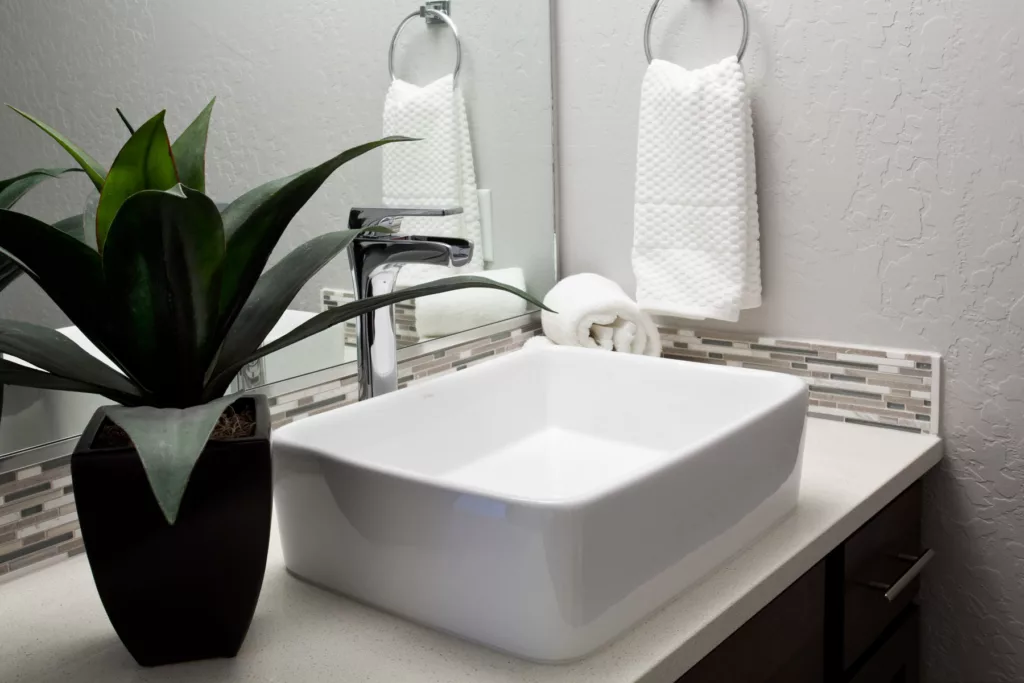 Close up of white rectangular bathroom sink sitting on countertop, stainless steal fixtures